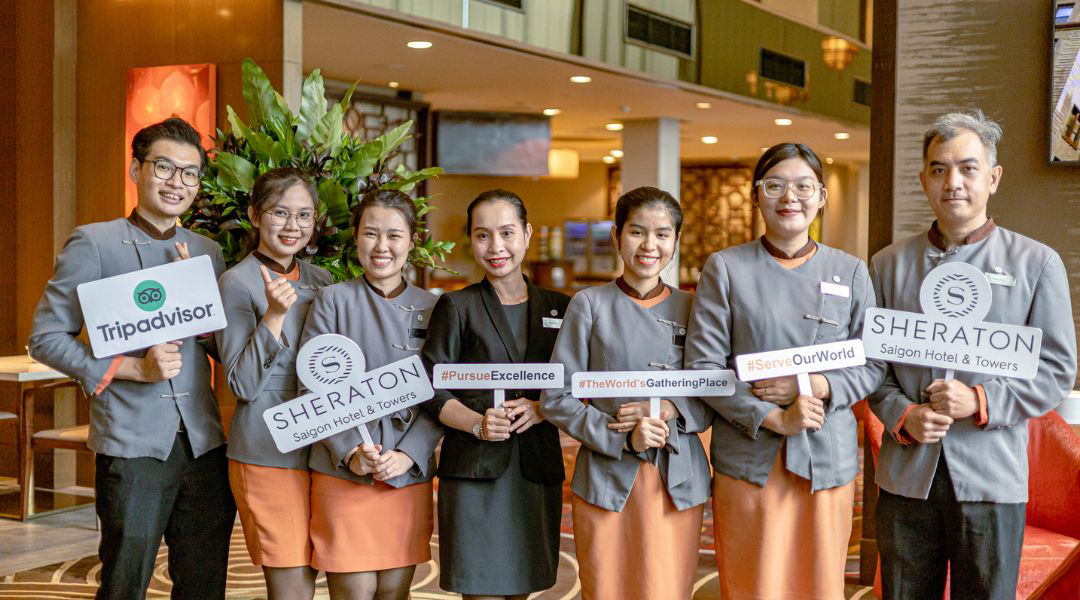 May đồng phục khách sạn Sheraton nổi bật cho nhân viên tại quầy lễ tân