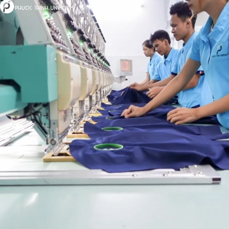 Nhân viên tại xưởng đang may logo lên áo
